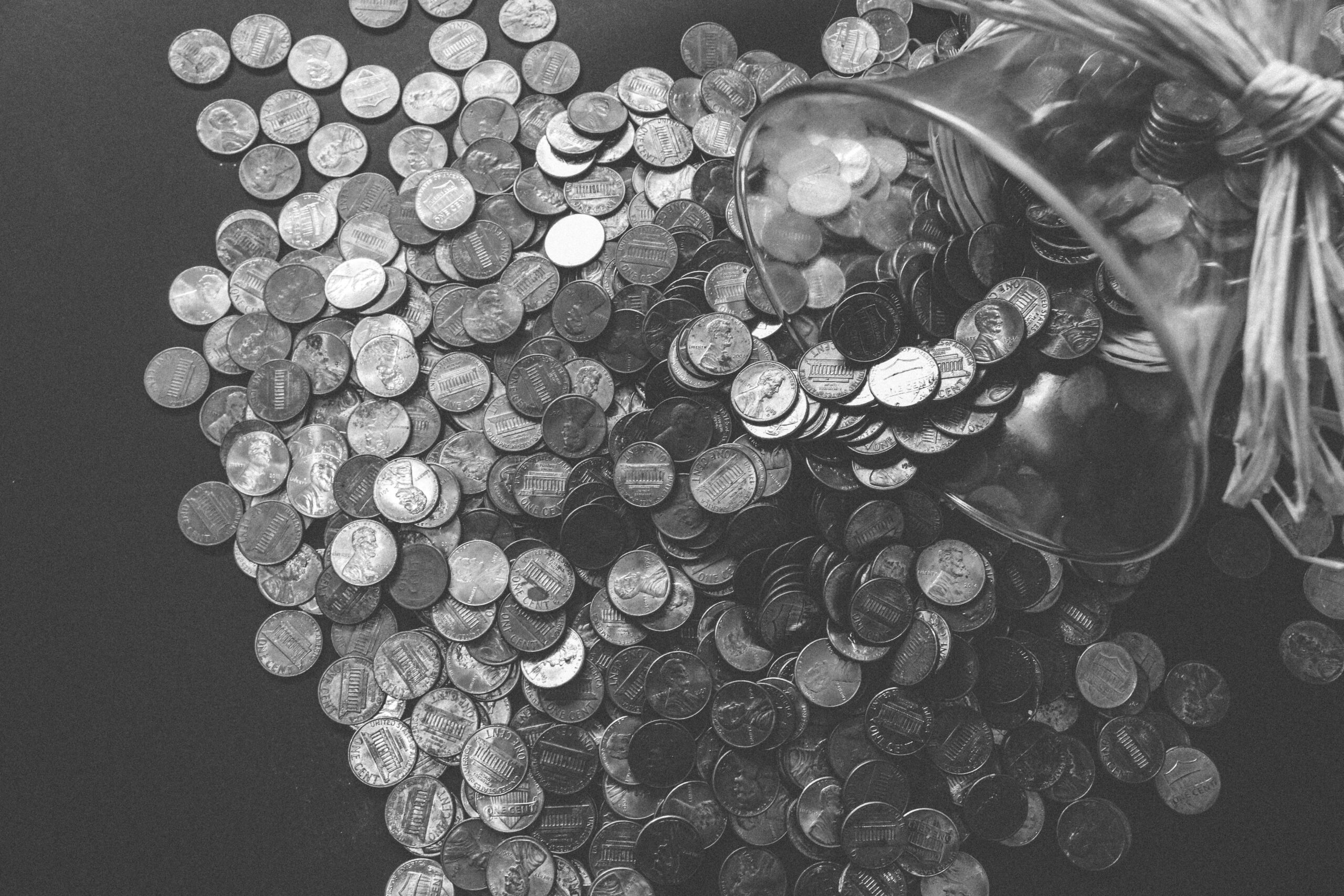 A black and white image of a savings jar spilling out coins, representing the benefits of a First Home Savings Account.